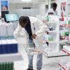 African American pharmacist organizing pharmacy shelves with medication, checking packaging and controlling stock levels to ensure order, cleanliness and efficiency in the pharmacy interior.